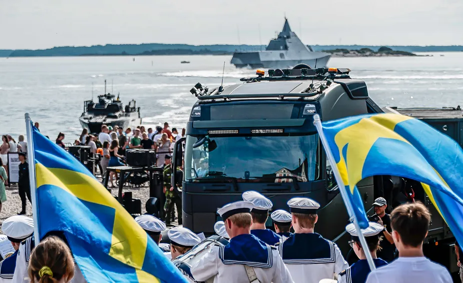 En grupp människor som står bredvid varandra nära ett vattenområde.