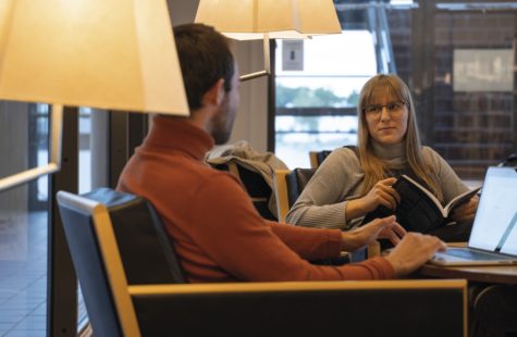 Foto på två studenter som sitter och studerar på biblioteket