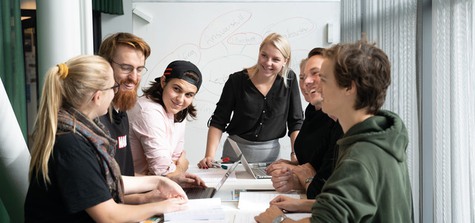 Foto på sju studenter som jobbar i ett grupparbete