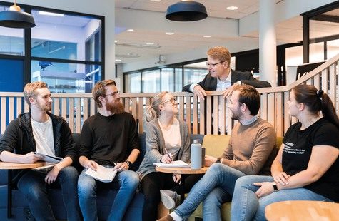 Foto på studenter i arbetsgrupp som samtalar med rektor