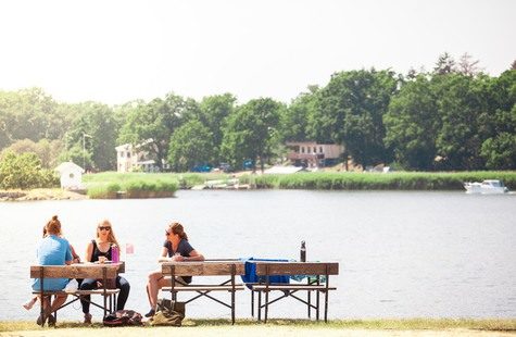 Foto på studenter som sitter och fikar på bänkar nere vid vattnet, Campus Karlskrona