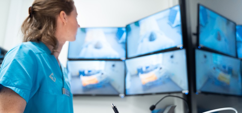Sjuksköterskestudent övervakar en sal på fyra skärmar