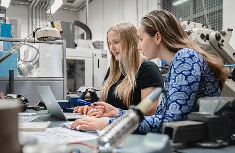 Två studenter vid arbetsbänk i maskinlabb