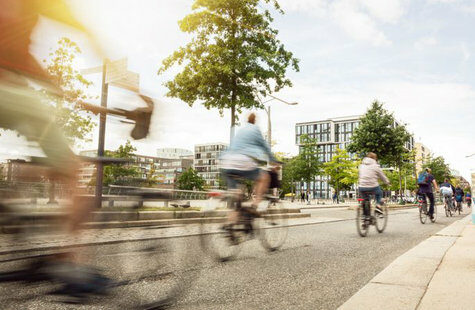 Cyklister som cyklar på led i stadsmiljö på en solig dag