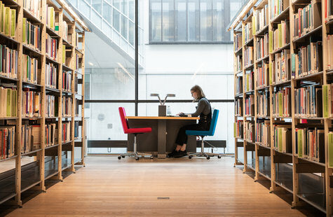 Tjej som läser vid ett bord i biblioteket