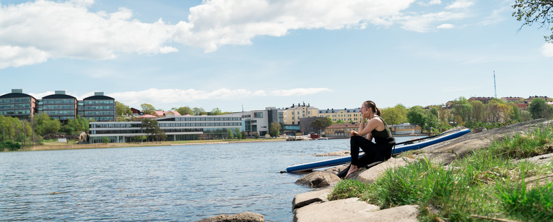 Tjej sitter på klippor och tittar ut över havet. 