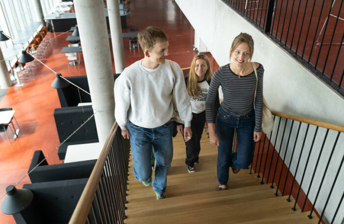 Tre studenter går upp för en trappa.