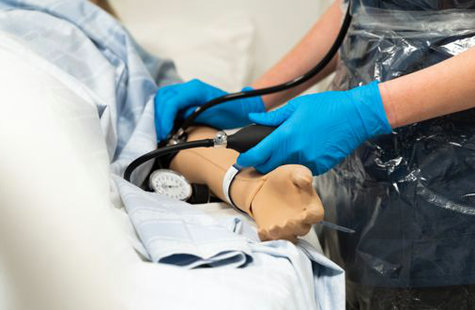 Student tar blodtryck på en övningsdocka